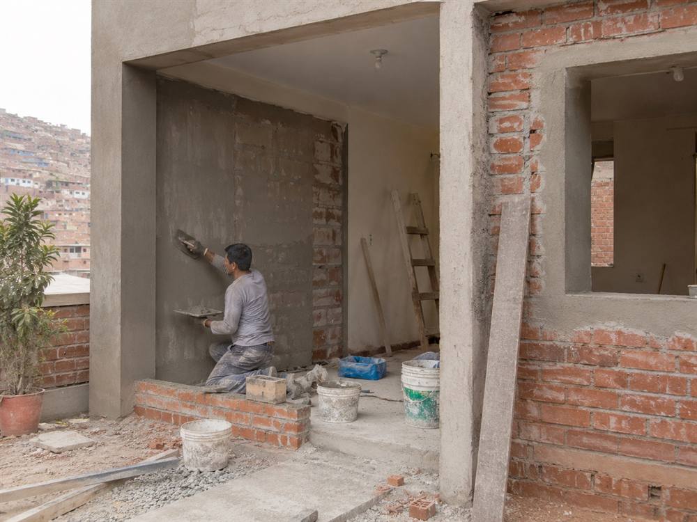 Operario aplicando revestimiento en una vivienda